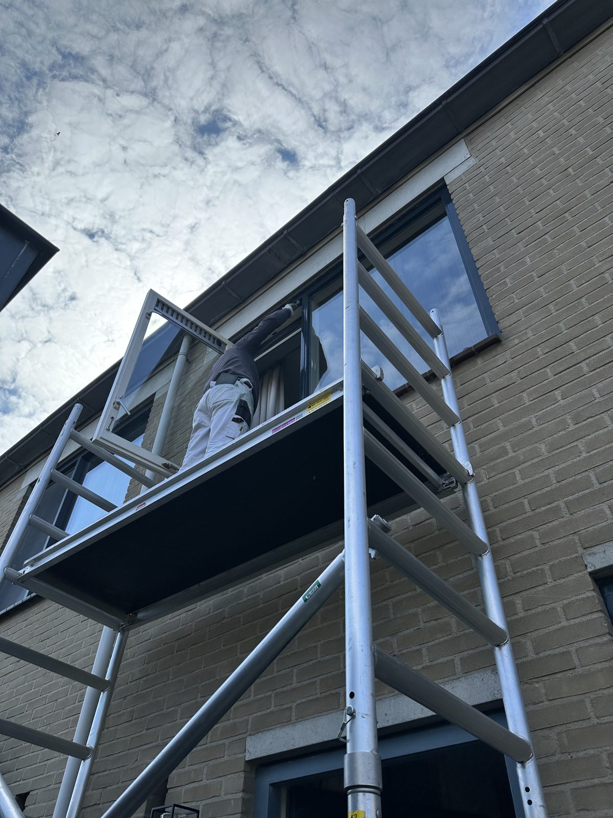 Scaffolding up along the brick facade for painting the upstairs window frames