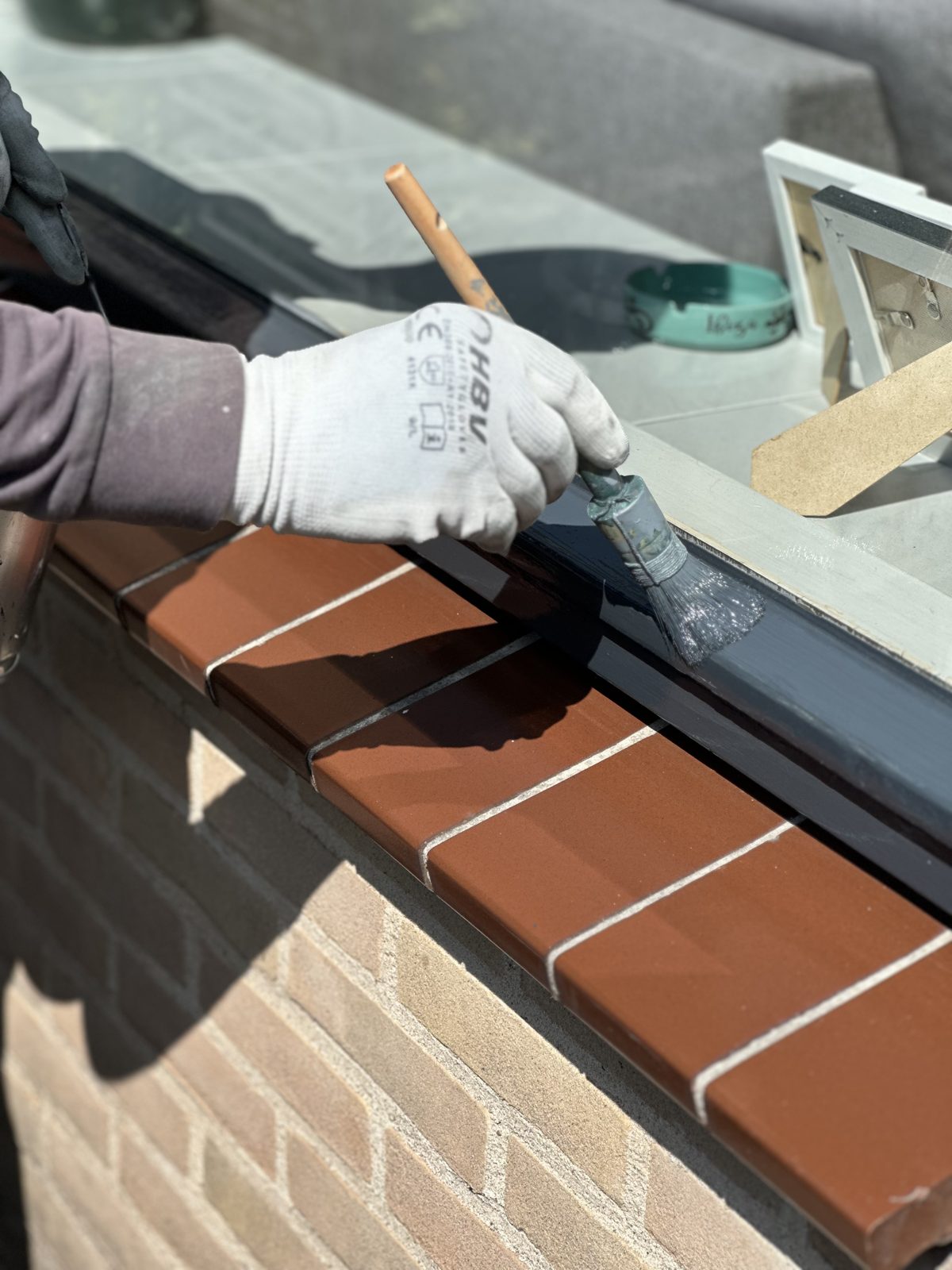 Close-up of a window sill being painted by hand