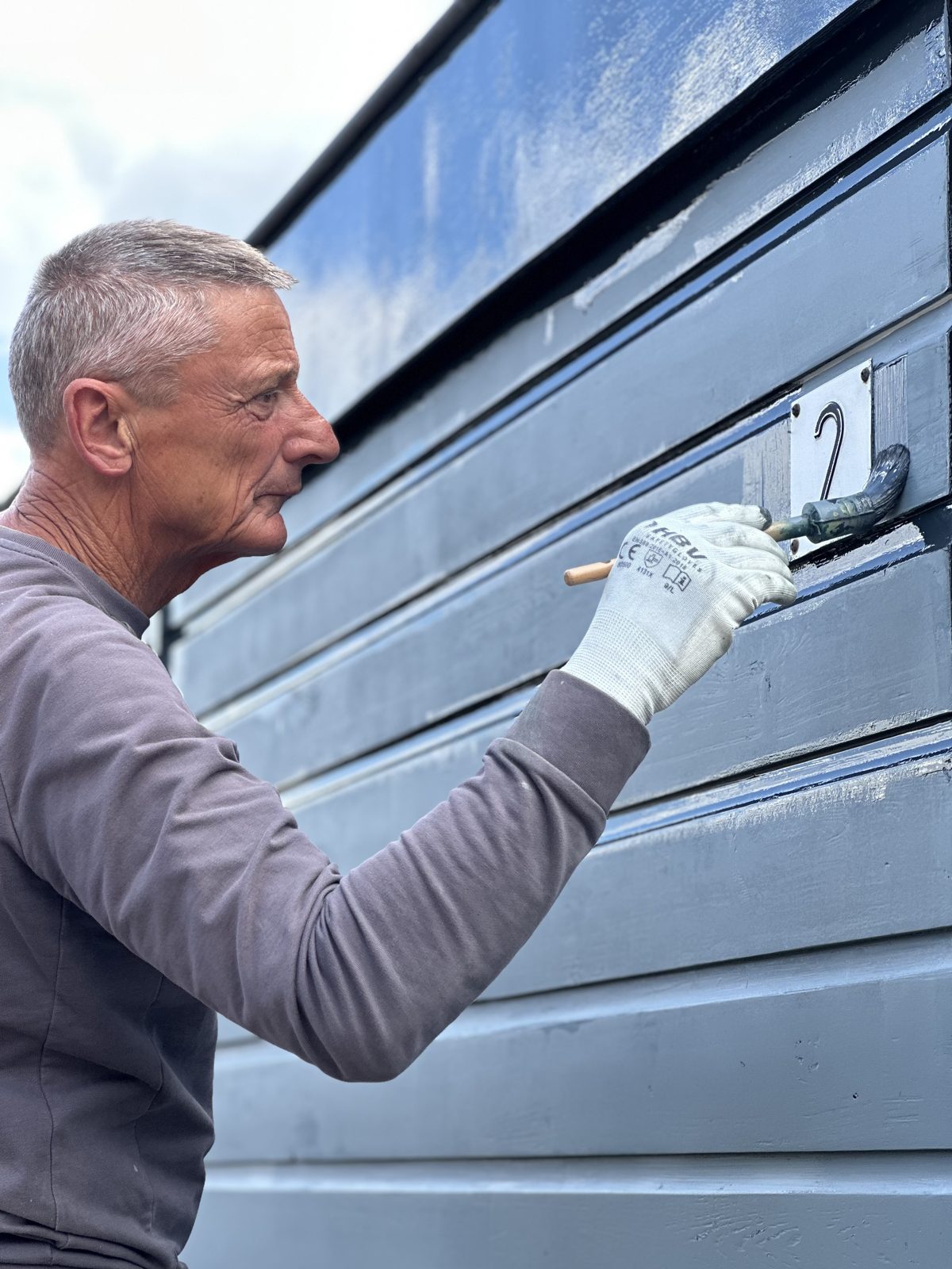 Ron painting cladding carefully around the house number